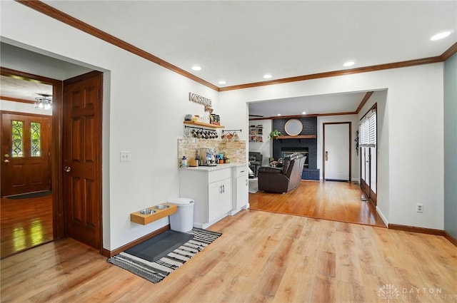 hall featuring crown molding, baseboards, recessed lighting, and light wood finished floors