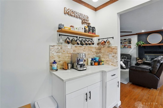 bar featuring crown molding, a fireplace, recessed lighting, tasteful backsplash, and light wood finished floors