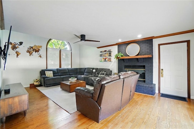 living room featuring light wood-style floors, a ceiling fan, baseboards, and a fireplace