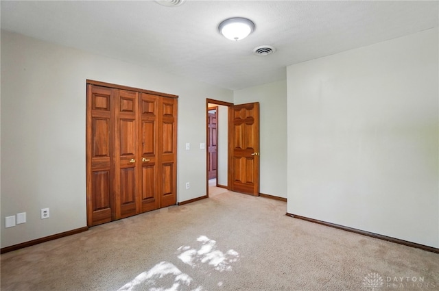 unfurnished bedroom featuring a closet, baseboards, light colored carpet, and visible vents