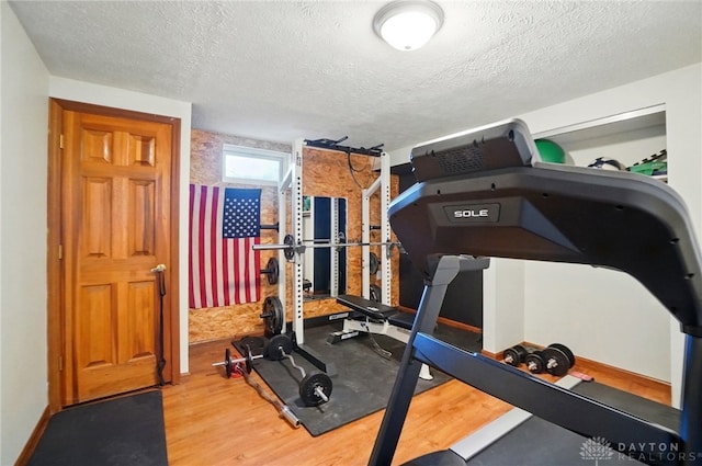 exercise area with a textured ceiling and wood finished floors