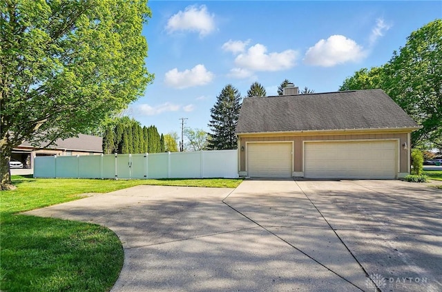 exterior space featuring fence, a yard, a chimney, and a detached garage