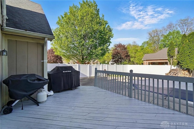 wooden deck with area for grilling and a fenced backyard