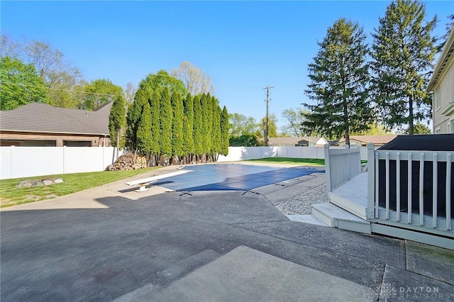 view of swimming pool with a diving board, a fenced in pool, a fenced backyard, and a patio area