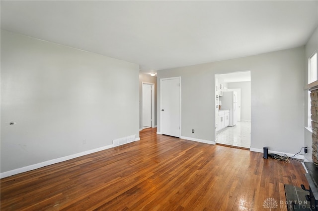 38 Homeview Dr, Harrison Twp, OH 45415 - unfurnished living room with baseboards, a fireplace with raised hearth, wood-type flooring, and visible vents