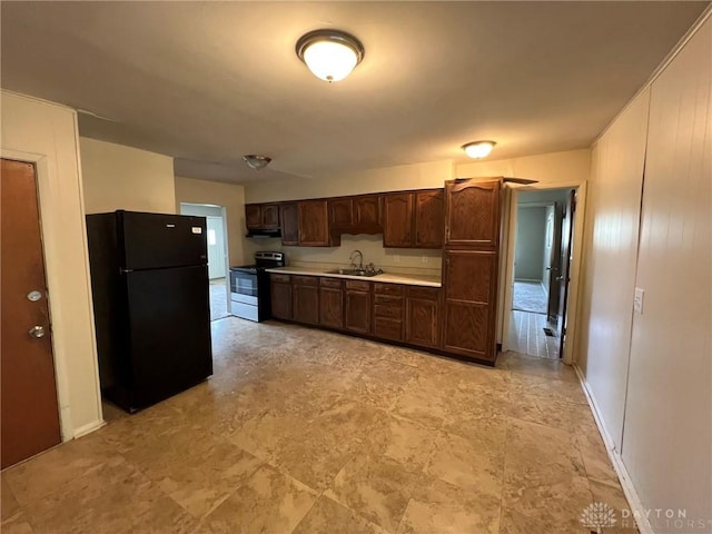 kitchen featuring range with electric cooktop, dark brown cabinets, a sink, light countertops, and freestanding refrigerator