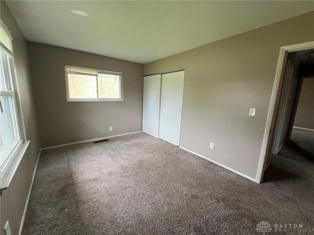 unfurnished bedroom with a closet, baseboards, carpet flooring, and visible vents