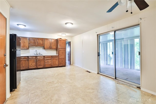5565 Ehrling Rd, Cincinnati, OH 45227 - kitchen with a sink, a ceiling fan, brown cabinetry, freestanding refrigerator, and light countertops