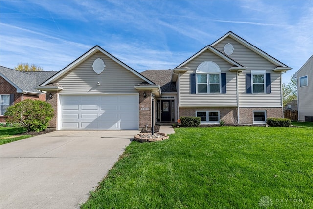 tri-level home with a front yard, central air condition unit, brick siding, concrete driveway, and an attached garage