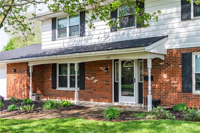 view of front of home with brick siding, a shingled roof, and covered porch