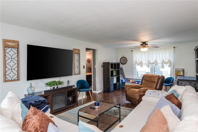 living area with baseboards, ceiling fan, and wood finished floors