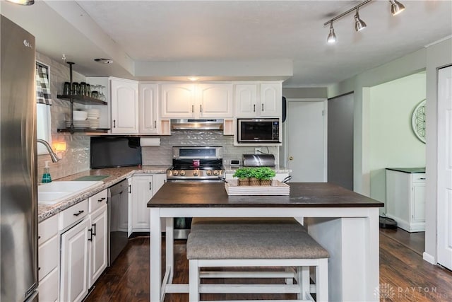 kitchen with under cabinet range hood, stainless steel appliances, white cabinets, and dark wood-style floors