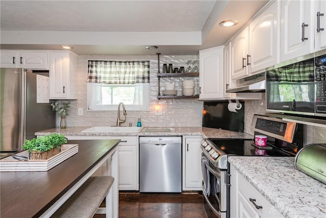 kitchen with a sink, appliances with stainless steel finishes, under cabinet range hood, and white cabinetry