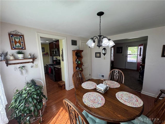 dining area featuring visible vents, baseboards, wood finished floors, and a notable chandelier