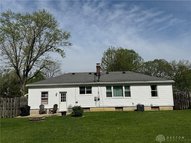 back of house with a yard, fence, a chimney, and an outdoor fire pit