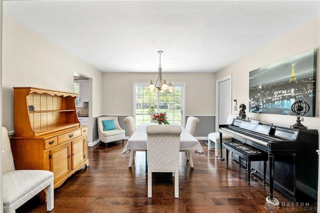 dining room featuring dark wood-style flooring, baseboards, and a chandelier