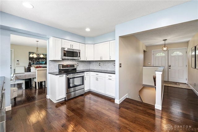 kitchen with white cabinets, dark countertops, a notable chandelier, stainless steel appliances, and dark wood-style floors