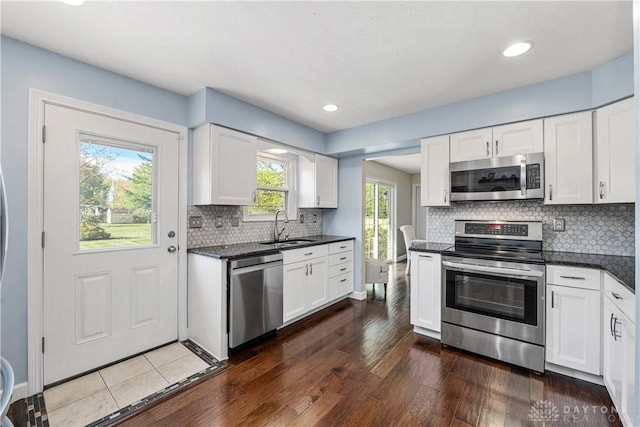 kitchen with a sink, appliances with stainless steel finishes, dark wood finished floors, and white cabinetry