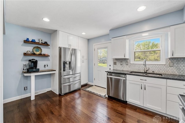 kitchen with white cabinets, a sink, stainless steel appliances, baseboards, and tasteful backsplash