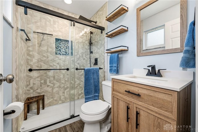 full bath with vanity, a stall shower, toilet, and wood finished floors