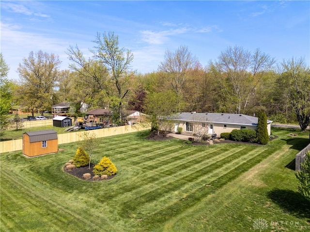 view of yard featuring fence, an outdoor structure, and a shed