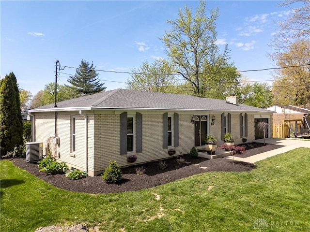 view of front of house featuring a chimney, a garage, brick siding, central AC, and a front lawn