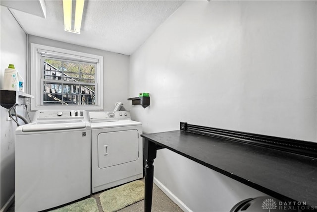 clothes washing area featuring washer and dryer, a textured ceiling, laundry area, and baseboards