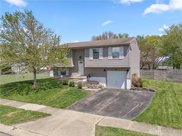 bi-level home featuring a garage, a front lawn, fence, and driveway