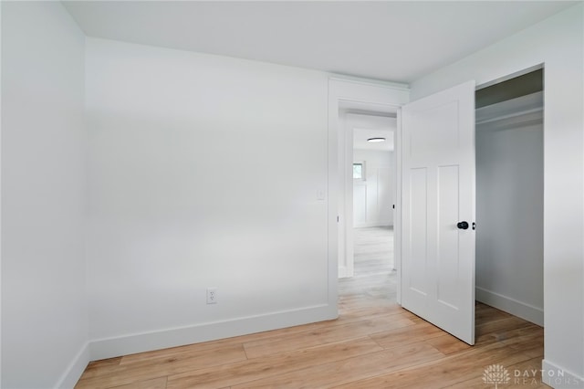unfurnished bedroom with baseboards, a closet, and light wood finished floors