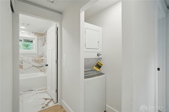 laundry room with laundry area, marble finish floor, stacked washing maching and dryer, and baseboards