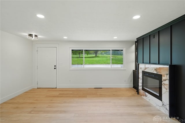 unfurnished living room with recessed lighting, light wood-style flooring, baseboards, and a fireplace