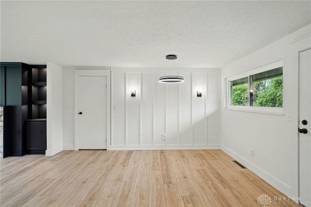 interior space with baseboards, visible vents, and light wood-type flooring