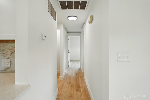 hall with visible vents, light wood-style flooring, and baseboards