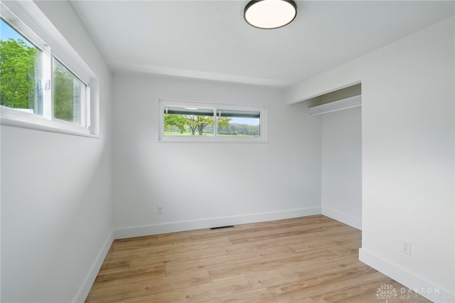 unfurnished bedroom featuring visible vents, light wood-style floors, baseboards, and a closet