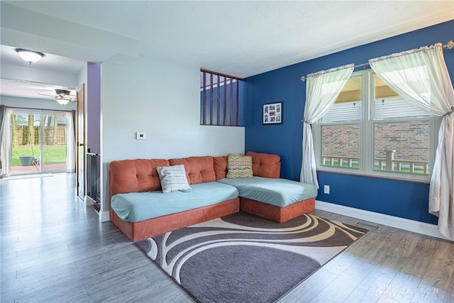 living area with ceiling fan, a textured ceiling, visible vents, wood finished floors, and baseboards