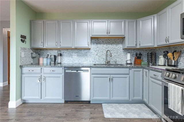 kitchen with a sink, appliances with stainless steel finishes, light wood-type flooring, and light stone counters