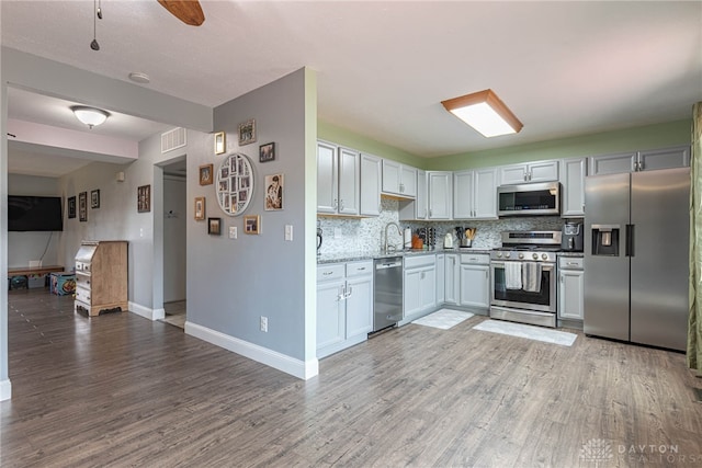 kitchen featuring backsplash, visible vents, baseboards, light wood-style floors, and stainless steel appliances