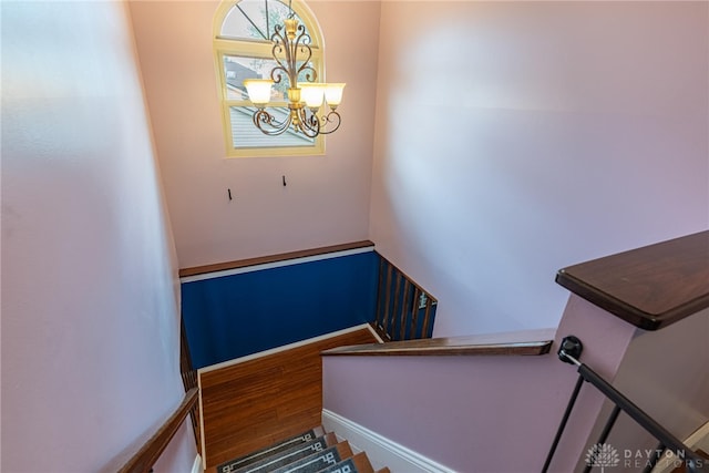 stairs featuring wood finished floors and a chandelier