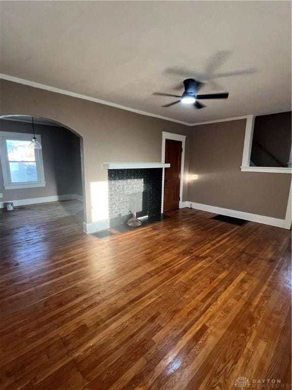 unfurnished living room with baseboards, arched walkways, ceiling fan, and dark wood-style floors