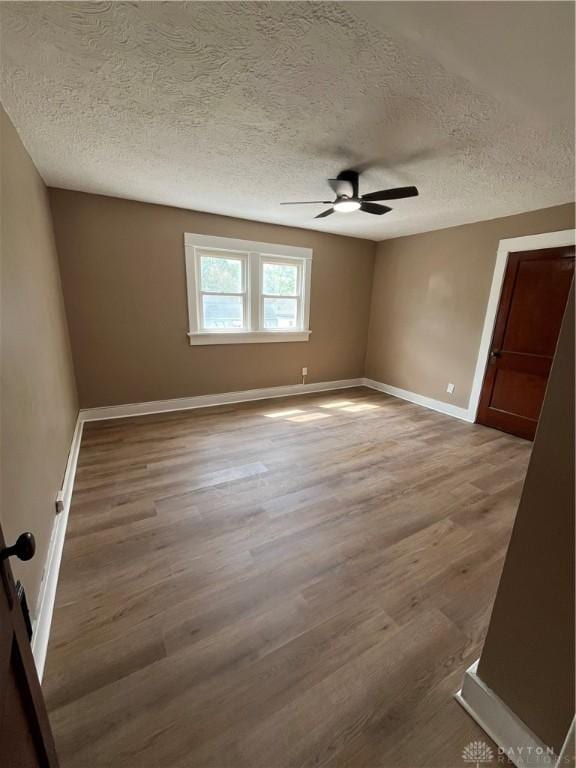 spare room featuring baseboards, a textured ceiling, ceiling fan, and wood finished floors