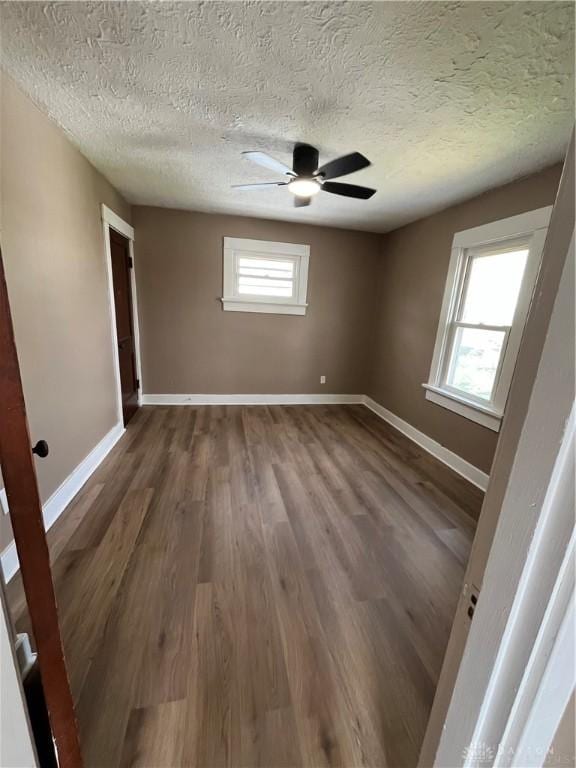 spare room with baseboards, a ceiling fan, a textured ceiling, and wood finished floors