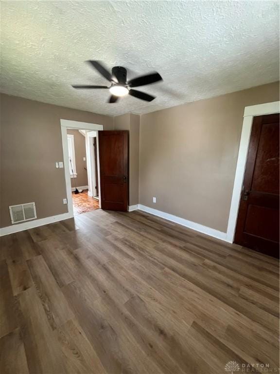 empty room featuring baseboards, a ceiling fan, wood finished floors, and visible vents