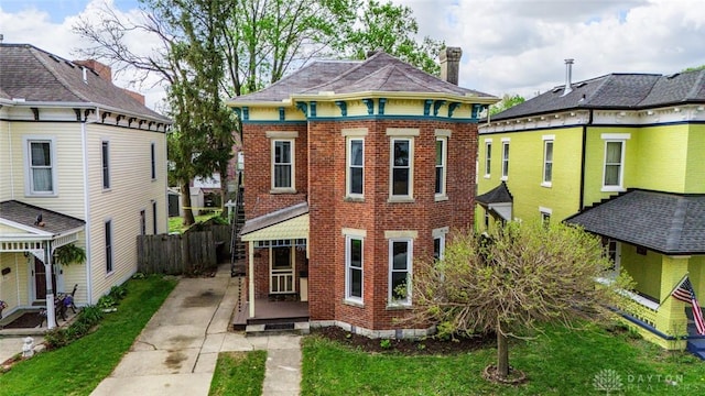 rear view of property featuring fence, a chimney, a lawn, and brick siding