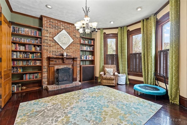 living area with ornamental molding, a brick fireplace, hardwood / wood-style floors, recessed lighting, and a chandelier