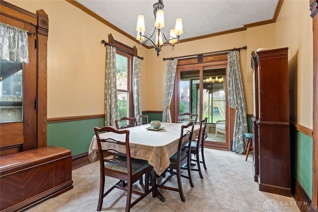 carpeted dining room featuring an inviting chandelier, ornamental molding, and wainscoting