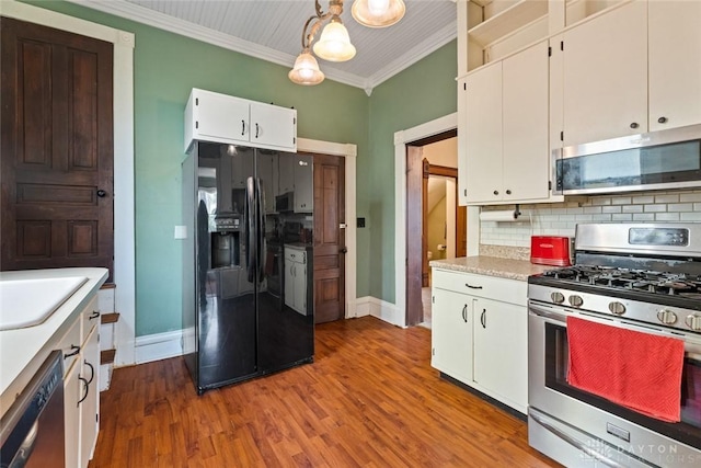 kitchen with light countertops, stainless steel appliances, baseboards, decorative backsplash, and ornamental molding