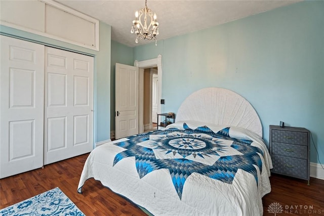 bedroom with baseboards, a closet, wood finished floors, and a notable chandelier