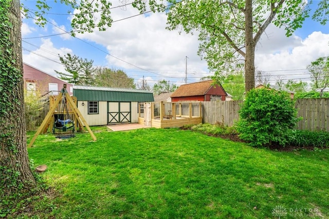 view of yard with a storage shed, an outbuilding, a fenced backyard, and a playground