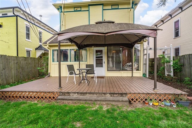 rear view of house with a gazebo, a fenced backyard, a lawn, and a deck