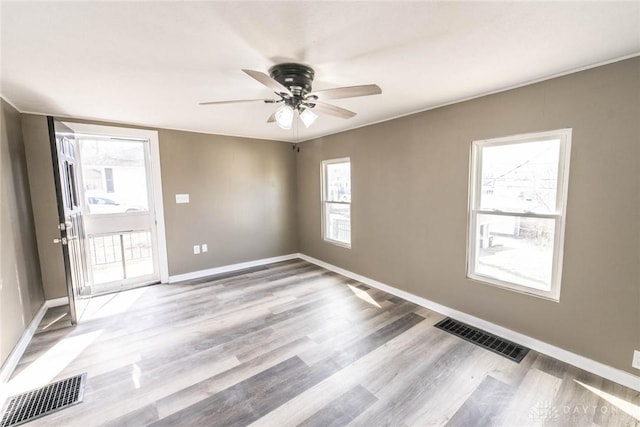 empty room featuring light wood-style floors, baseboards, a ceiling fan, and visible vents